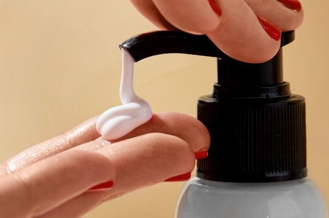 person pumping out body lotion onto fingers