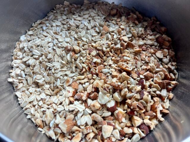 granola ingredients - oats and nuts and seeds in metal mixing bowl