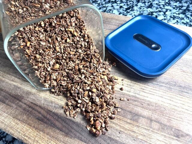 granola spilling out of container onto cutting board